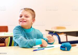Young boy using a pencil and smiling