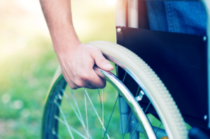 A hand on the wheel of a wheelchair.