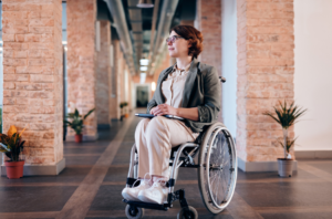 woman sitting in a wheelchair holding a tablet.