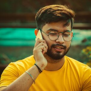 Man in yellow shirt holding a phone to his ear.
