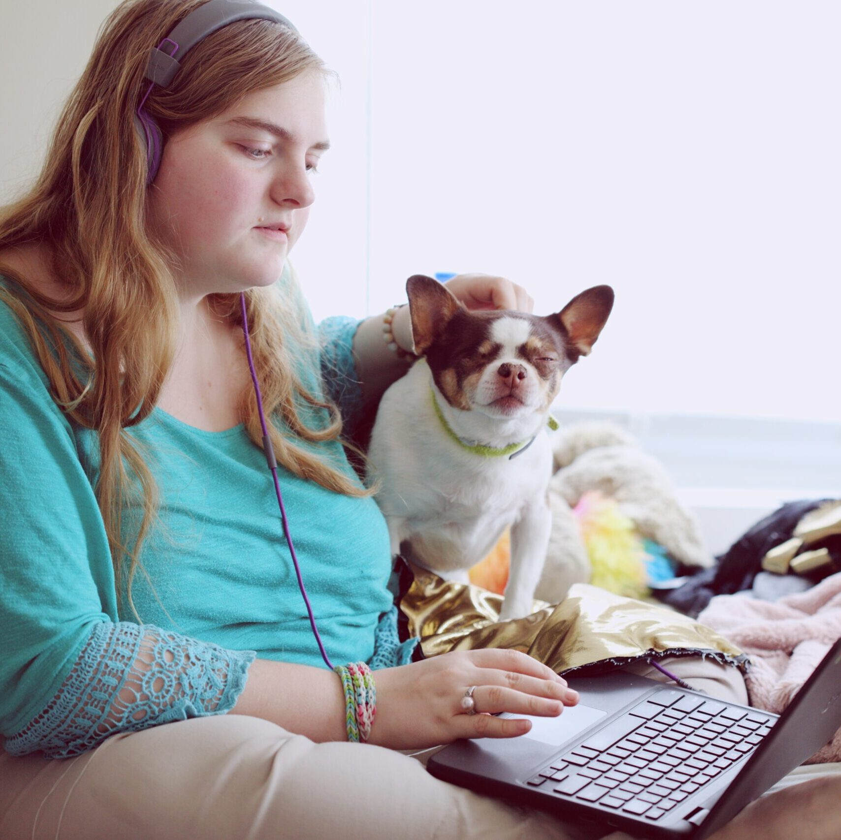 Young woman sitting on her bed looking at her laptop